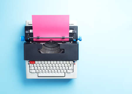 Typewriter with pink paper over blue background, top viewの写真素材