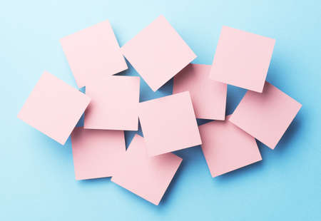 Paper squares disorganized over blue background, top view