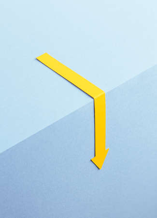 Yellow arrow pointing down over blue backgroundの写真素材