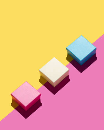 Simple gift boxes over pink and yellow backgroundの写真素材