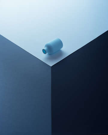 Small blue bottle rolling over a cubeの写真素材