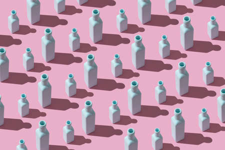 Colorful painted glass bottles organized in a row over pink background