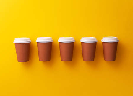 Multiple disposable coffee cups organized over yellow backgroundの写真素材