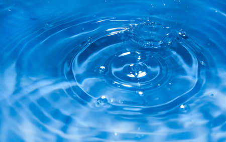 Macro view of a drop entering the blue water Macro view of a drop entering the blue water