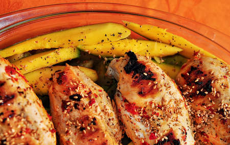 Pieces of chicken breast with mango in transparent bowlの写真素材