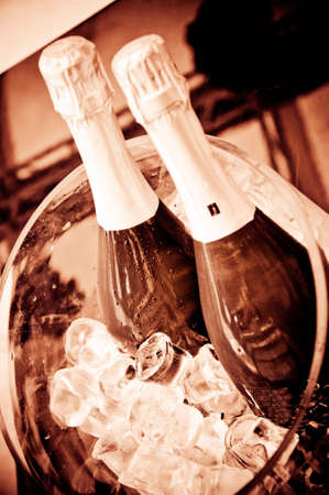 Close-up of 2 cold bottles of champagne on ice with sepia filterの写真素材