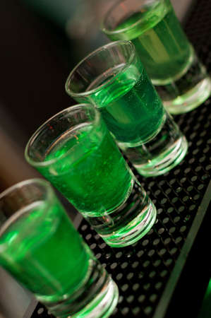 Green liquid in shot glasses standing on the counter.の写真素材