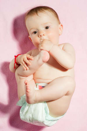 Adorable little seven months old baby laying in his diper on a fluffy pink blanket, isolatedの写真素材