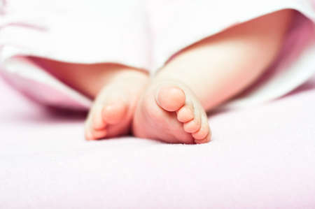 Little Feet of a newborn child in a bright enviromentの写真素材