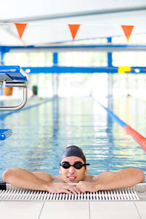 Male Swimmer resting after several laps in the indoor swimming poolの写真素材