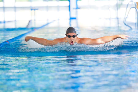 Man breathing while swimming  butterfly strokes in competition wearing swimming goggles and capの写真素材