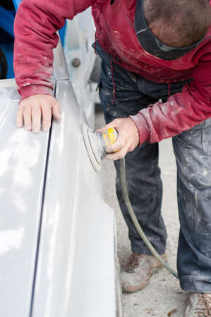 Auto mechanic prepairing the car for paint job by appling polish with the power buffer machineの写真素材