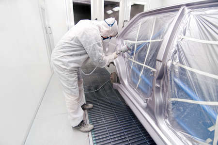 auto mechanic spraying paint on a car in a special boothの写真素材