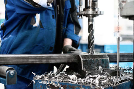industrial tehnician working on a drilling machine - making a hole in a metal barの写真素材