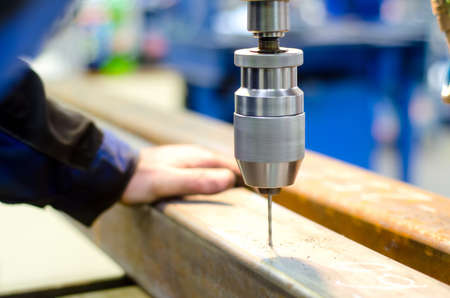 industrial worker drilling a hole with automatic drill machine in a metal barの写真素材