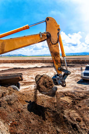 Industrial construction site with working excavator that loads soil into dumper truck