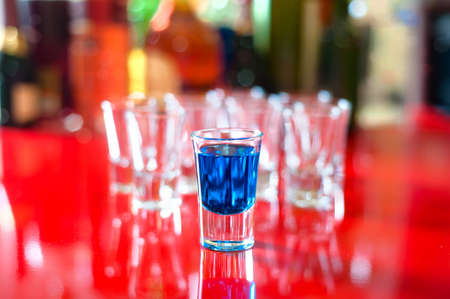 Blue hot alcoholic drink in shot glass on bar の写真素材