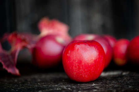 Organic red apples from autumn harvest in agriculture theme against wooden backgroundの写真素材