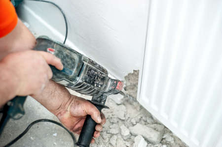 worker using a drilling machine to make holes in walls, during constructionの写真素材