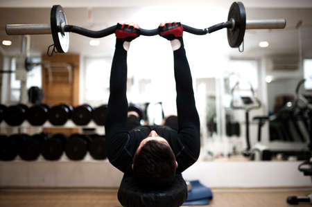 bodybuilder in the gym, working with the barbell the triceps and biceps
