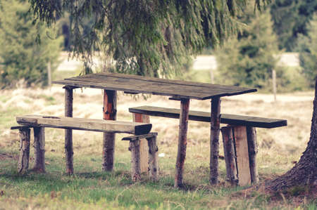 Vintage photo of a Wooden, rustic bench and picnic table, in the forest