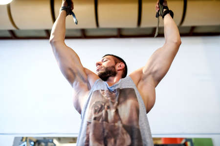 bodybuilder doing chin ups, working out at the gym