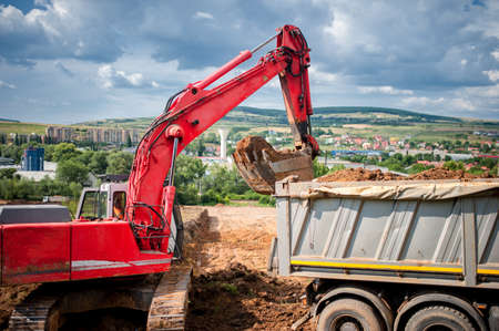 industrial excavator loader with rised backhoe standing in sandpit and digging in pit 