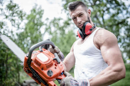 portrait of aggressive muscular male lumberjack, woodworker with chainsaw in hand, posingの写真素材