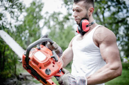 portrait of angry muscular male lumberjack, woodworker with chainsaw in hand, posing の写真素材