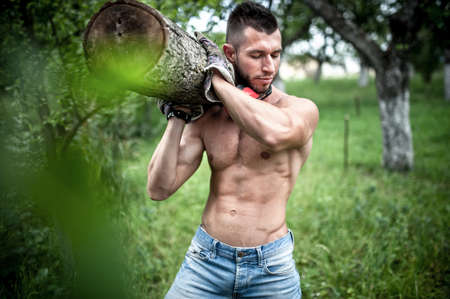 male model carrying and cutting wood logs for firewood の写真素材