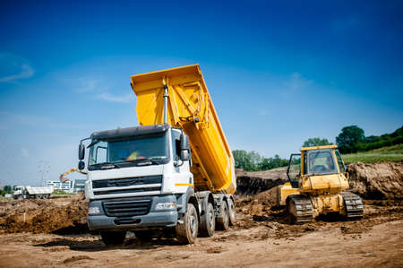 dumper truck and bulldozer at highway road construction site