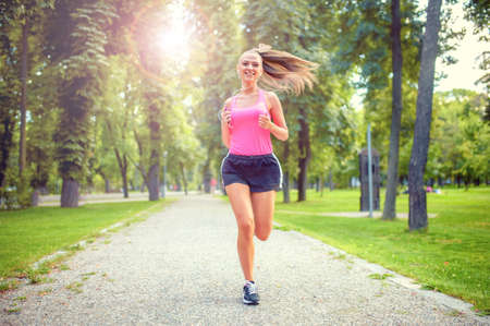 healthy and happy woman running in urban park with headphones and music の写真素材