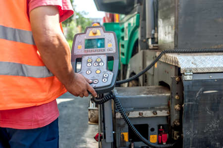close up of worker hand operating asphalt paver machinery on construction site of roads and repairing worksの写真素材