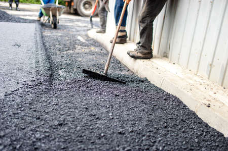 worker with special tool working with fresh asphalt and bitumenの写真素材
