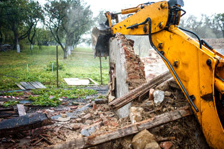 Excavator demolishing a concrete wall.bulldozer loading demolition debris and concrete waste for recycling at construction site.の写真素材