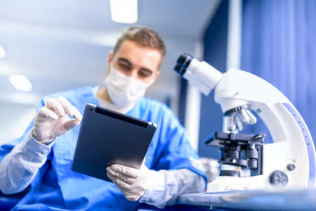pharmacist working on prescription drugs with modern tablet and microscopeの写真素材