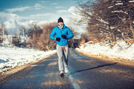 Muscular athlete man jogging outdoor on snow, training for box practiceの写真素材