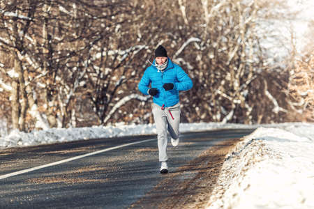 Man fitness concept - running and jogging, outdoor training in snow on a cold sunny dayの写真素材