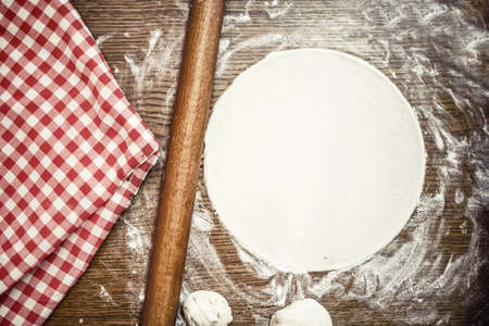 Perfect pizza dough with fresh, bio ingredients and flour on wooden tableの写真素材