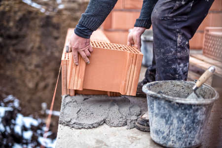 Construction site of new house, worker building the brick wall with trowel, cement and mortarの写真素材