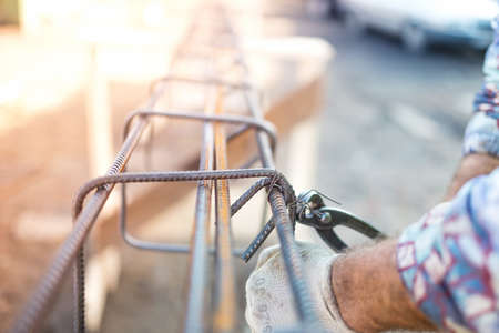 Details of infrastructure - Construction worker hands securing steel bars with wire rod for reinforcement of concreteの写真素材