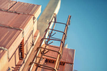 reinforcement steel bars on pillars and layers of bricks on new house construction - details of building structure on construction siteの写真素材