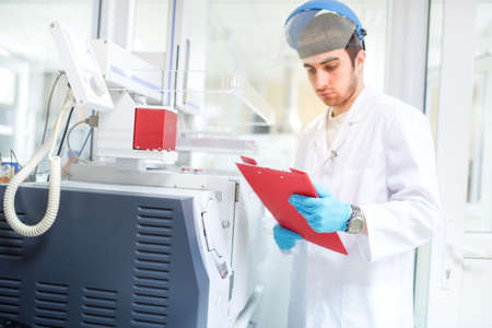 Scientist or doctor using clipboard and reading experiment information from computer