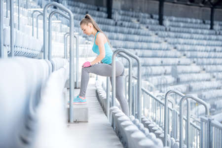 Female fitness trainer working out on stairs, preparing for training - stretching and doing squatsの写真素材