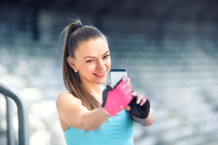 Portrait of beautiful fitness woman taking selfie with phone camera. Healthy woman training and taking picturesの写真素材