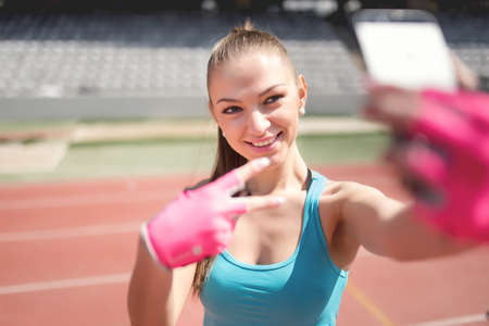 Portrait of a charming woman taking a selfie, a picture of herself during training. Training, fitness and technology outdoorsの写真素材