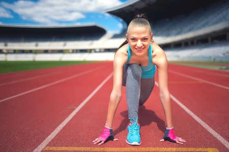 Active female runner preparing for a track contest, enjoying a workout, training and working out. Fitness girl jogging on stadium track. Instagram filter effectの写真素材