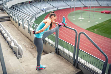 Female athlete training and stretching for warming up on the stairs. Fitness girl training and runningの写真素材