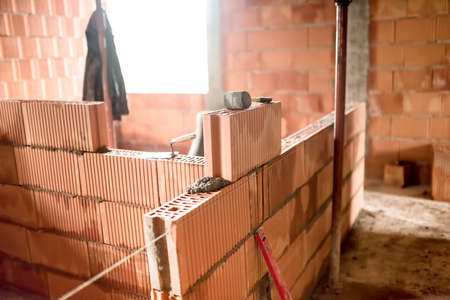bricklayer building new house with brick walls, interior roomsの写真素材