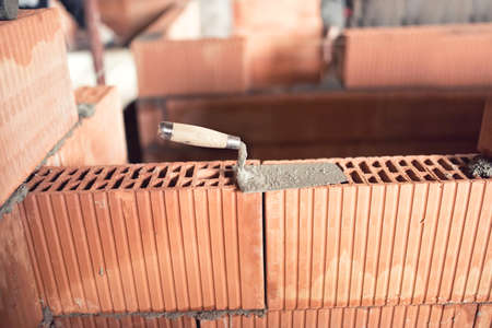 Construction site details and tools, trowel, putty knife on top of brick layer on interior wallsの写真素材